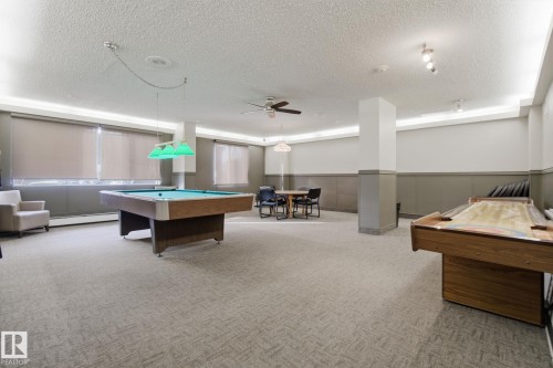 Rec room with billiards table, ceiling fan, a textured ceiling, wainscoting, and a baseboard radiator - 1312 13910 Stony Plain Road, Edmonton, AB - Indoor Photo Showing Other Room