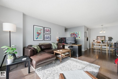Living area with a desk, dark wood-style floors, and a chandelier - 1312 13910 Stony Plain Road, Edmonton, AB - Indoor Photo Showing Living Room