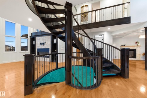Stairway featuring a stone fireplace, a high ceiling, and hardwood / wood-style flooring - 4811 Woolsey Lane, Edmonton, AB - Indoor Photo Showing Other Room