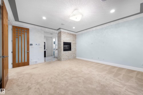 Unfurnished living room featuring light carpet, a textured ceiling, a fireplace, and recessed lighting - 4811 Woolsey Lane, Edmonton, AB - Indoor Photo Showing Other Room