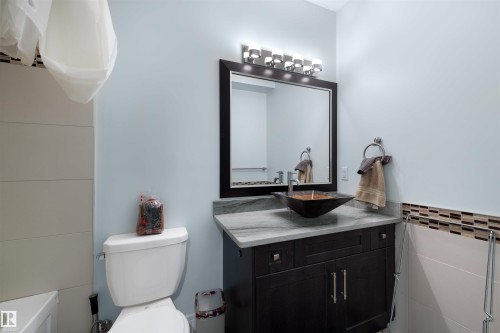 Bathroom with vanity, a bath, and tile walls - 4811 Woolsey Lane, Edmonton, AB - Indoor Photo Showing Bathroom