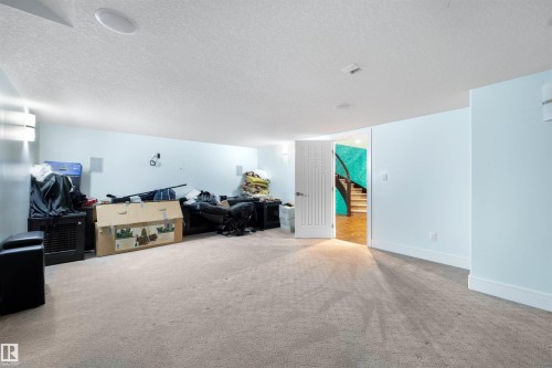 Carpeted living area featuring stairway and a textured ceiling - 4811 Woolsey Lane, Edmonton, AB - Indoor