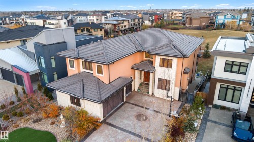View of front of property featuring a residential view, a gate, driveway, stucco siding, and a tiled roof - 4811 Woolsey Lane, Edmonton, AB - Outdoor