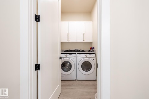 Laundry area with light wood finished floors, separate washer and dryer, and cabinet space - 7471 May Common, Edmonton, AB - Indoor Photo Showing Laundry Room