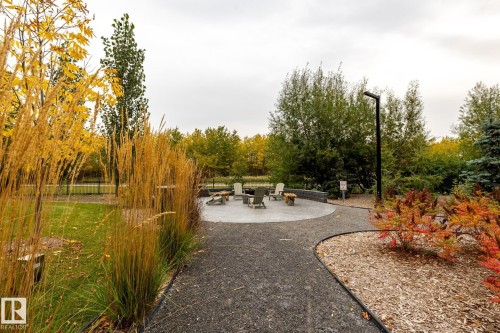 View of property's community with a patio, a fire pit, and view of wooded area - 7471 May Common, Edmonton, AB - Outdoor