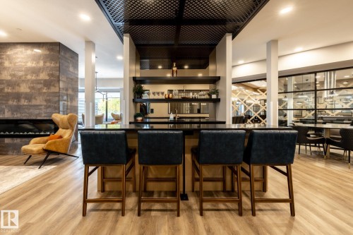 Indoor wet bar featuring open shelves, dark countertops, a tile fireplace, light wood-style flooring, and recessed lighting - 7471 May Common, Edmonton, AB - Indoor Photo Showing Dining Room