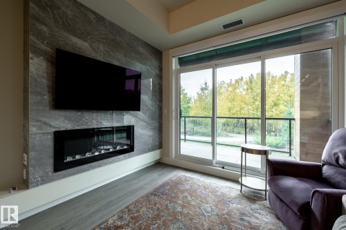 Living area featuring a premium fireplace and wood finished floors - 7471 May Common, Edmonton, AB - Indoor Photo Showing Living Room With Fireplace