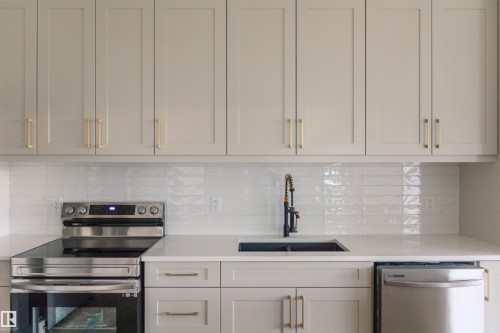 Kitchen featuring stainless steel appliances, light stone countertops, and tasteful backsplash - 163 Starling Way, Fort Saskatchewan, AB - Indoor Photo Showing Kitchen With Upgraded Kitchen