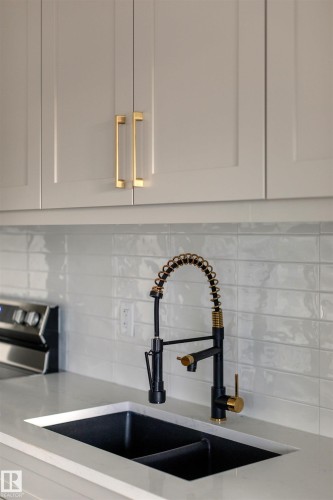 Kitchen view of backsplash, light stone counters, and stainless steel range oven - 163 Starling Way, Fort Saskatchewan, AB - Indoor Photo Showing Kitchen With Double Sink