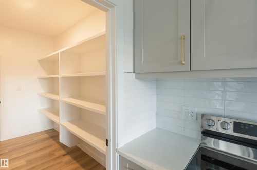 Detailed view of electric range, light wood-type flooring, gray cabinets, backsplash, and light countertops - 163 Starling Way, Fort Saskatchewan, AB - Indoor