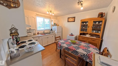 Kitchen with white appliances, a textured ceiling, light wood-style flooring, white cabinets, and light countertops - 3122 142 Avenue, Edmonton, AB - Indoor
