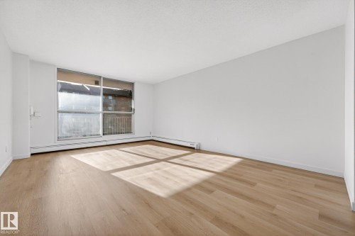 Empty room featuring light wood finished floors and a baseboard heating unit - 207 11007 83 Avenue, Edmonton, AB - Indoor Photo Showing Other Room