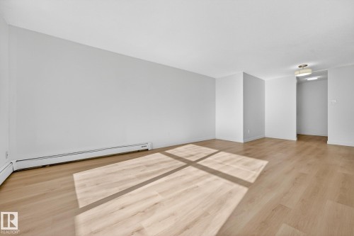 Spare room with light wood-type flooring and a baseboard radiator - 207 11007 83 Avenue, Edmonton, AB - Indoor Photo Showing Other Room