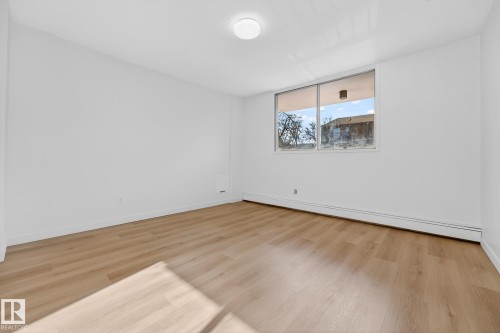 Spare room with baseboard heating and light wood-type flooring - 207 11007 83 Avenue, Edmonton, AB - Indoor Photo Showing Other Room