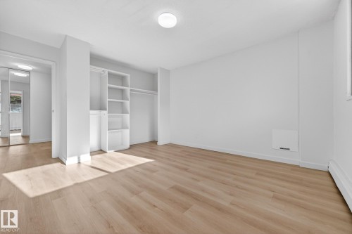 Unfurnished bedroom featuring light wood finished floors, a baseboard heating unit, and a closet - 207 11007 83 Avenue, Edmonton, AB - Indoor Photo Showing Other Room