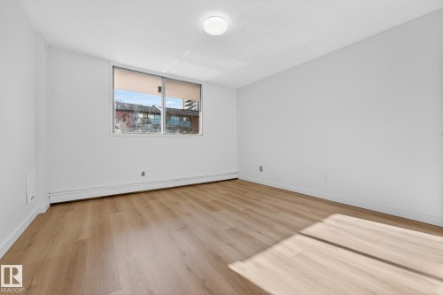 Empty room with a baseboard radiator and light wood finished floors - 207 11007 83 Avenue, Edmonton, AB - Indoor Photo Showing Other Room