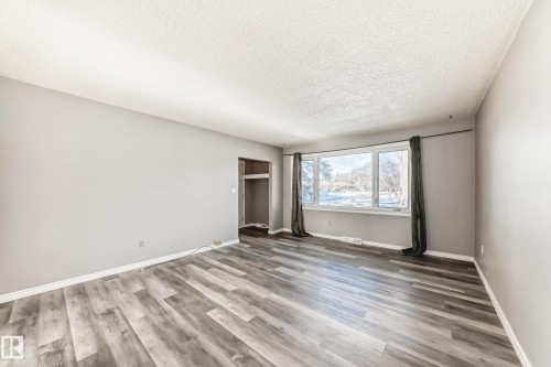 Unfurnished bedroom featuring light wood-style flooring, a textured ceiling, and a closet - 8639 64 Avenue Nw, Edmonton, AB - Indoor Photo Showing Other Room