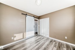 Unfurnished bedroom with a barn door, light wood-style flooring, and a closet - 