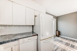 Kitchen featuring white appliances, white cabinets, light wood-style floors, dark countertops, and decorative backsplash - 
