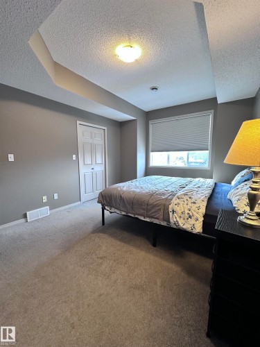 Bedroom with carpet floors and a textured ceiling - 23 4821 Terwillegar Common, Edmonton, AB - Indoor Photo Showing Bedroom
