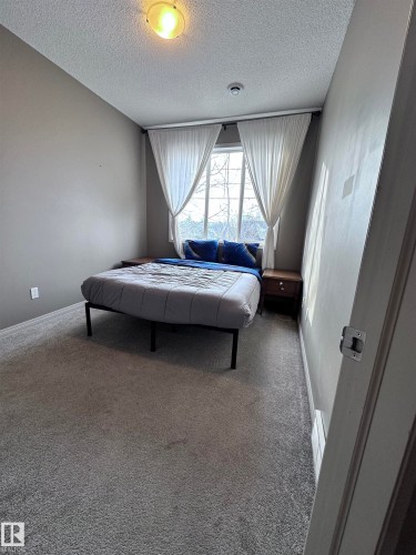 Carpeted bedroom featuring a textured ceiling - 23 4821 Terwillegar Common, Edmonton, AB - Indoor Photo Showing Bedroom