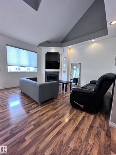 Living area featuring a high textured ceiling, dark wood finished floors, and a fireplace - 23 4821 Terwillegar Common, Edmonton, AB - Indoor Photo Showing Living Room With Fireplace