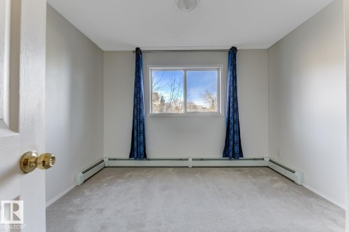 Spare room with light carpet and baseboard heating - 237 17447 98A Avenue, Edmonton, AB - Indoor Photo Showing Other Room