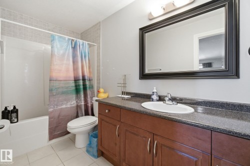 Full bath with shower / bathtub combination with curtain, vanity, and light tile patterned flooring - 48 Douglas Crescent, Leduc, AB - Indoor Photo Showing Bathroom