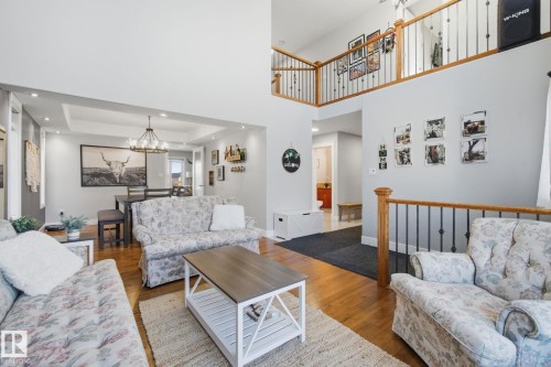 Living room with hardwood / wood-style flooring, hanging lights, and a high ceiling - 48 Douglas Crescent, Leduc, AB - Indoor Photo Showing Living Room