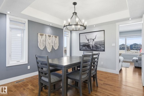 Dining space with hardwood / wood-style flooring, a chandelier, and a tray ceiling - 48 Douglas Crescent, Leduc, AB - Indoor Photo Showing Dining Room