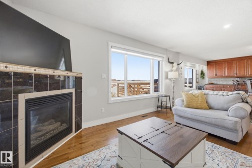 Living room with wood-type flooring and a tiled fireplace - 48 Douglas Crescent, Leduc, AB - Indoor Photo Showing Living Room With Fireplace