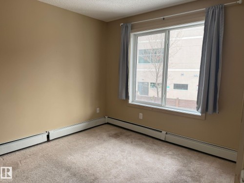 Spare room with a baseboard heating unit, carpet floors, and a textured ceiling - 211 340 Windermere Road, Edmonton, AB - Indoor Photo Showing Other Room