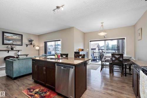 Kitchen featuring dark wood finish cabinetry, stainless steel appliances, open floor plan, dark wood-type flooring, and a textured ceiling - 33 Sutherland Street, Leduc, AB - Indoor Photo Showing Other Room