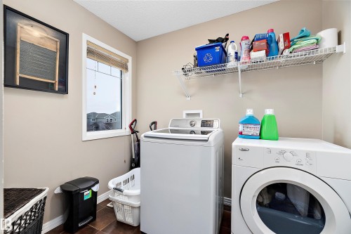 Laundry room with separate washer and dryer, a textured ceiling, and dark tile patterned floors - 33 Sutherland Street, Leduc, AB - Indoor Photo Showing Laundry Room