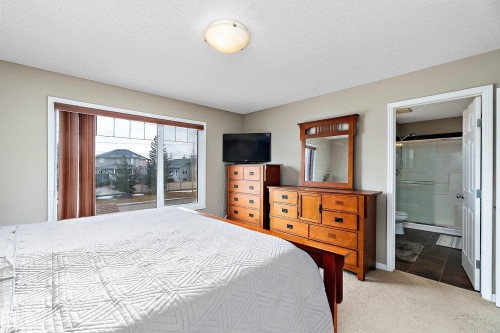 Bedroom with light colored carpet, a textured ceiling, and ensuite bathroom - 33 Sutherland Street, Leduc, AB - Indoor Photo Showing Bedroom