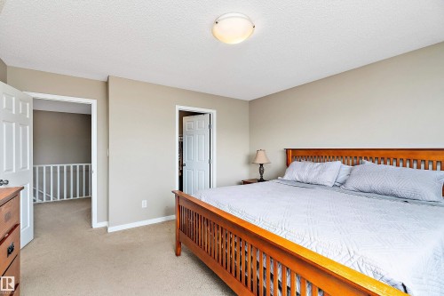 Bedroom with light colored carpet and a textured ceiling - 33 Sutherland Street, Leduc, AB - Indoor Photo Showing Bedroom