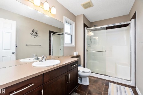 Bathroom featuring a shower stall, vanity, dark tile patterned flooring, and a textured ceiling - 33 Sutherland Street, Leduc, AB - Indoor Photo Showing Bathroom