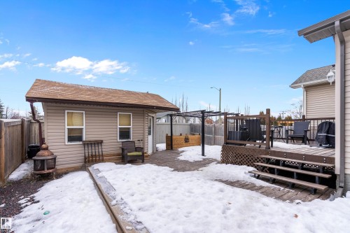 Snow covered house with a wooden deck, an outdoor structure, and a fenced backyard - 33 Sutherland Street, Leduc, AB - Outdoor With Exterior