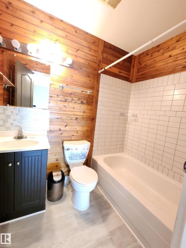 Full bathroom featuring vanity, bathing tub / shower combination, wood walls, and backsplash - 6 14320 80 Street, Edmonton, AB - Indoor Photo Showing Bathroom