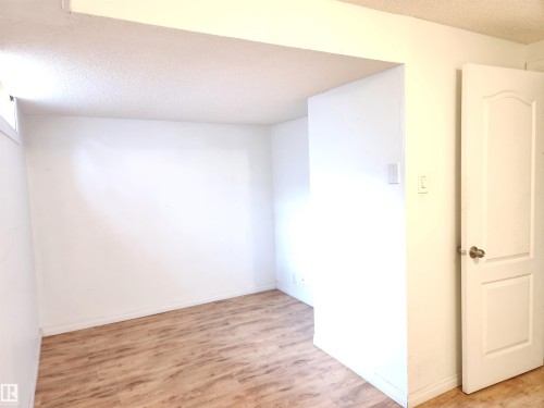 Empty room with a textured ceiling and light wood finished floors - 6 14320 80 Street, Edmonton, AB - Indoor Photo Showing Other Room