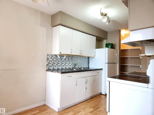 Kitchen with white appliances, dark countertops, light wood-style floors, a textured ceiling, and white cabinetry - 6 14320 80 Street, Edmonton, AB - Indoor Photo Showing Kitchen