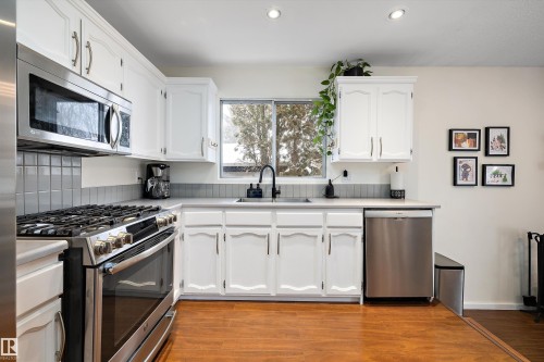Kitchen with stainless steel appliances, white cabinetry, light wood-type flooring, and recessed lighting - 12 Beacon Crescent, St. Albert, AB - Indoor Photo Showing Kitchen