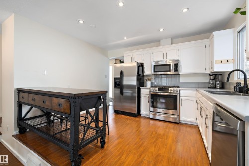 Kitchen featuring white cabinetry, stainless steel appliances, light countertops, light wood-style flooring, and recessed lighting - 12 Beacon Crescent, St. Albert, AB - Indoor Photo Showing Kitchen With Double Sink