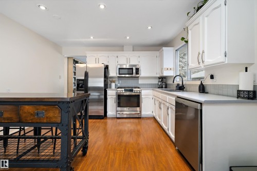 Kitchen featuring stainless steel appliances, white cabinets, light wood-style flooring, light countertops, and recessed lighting - 12 Beacon Crescent, St. Albert, AB - Indoor Photo Showing Kitchen