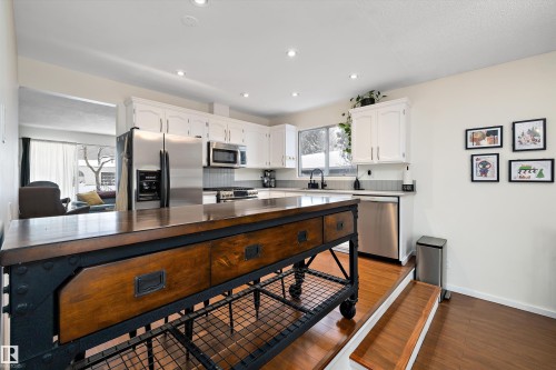 Kitchen with white cabinetry, stainless steel appliances, light wood finished floors, light countertops, and recessed lighting - 12 Beacon Crescent, St. Albert, AB - Indoor Photo Showing Kitchen