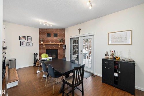Dining room with track lighting, dark wood-type flooring, a brick fireplace, french doors, and a textured ceiling - 12 Beacon Crescent, St. Albert, AB - Indoor Photo Showing Dining Room