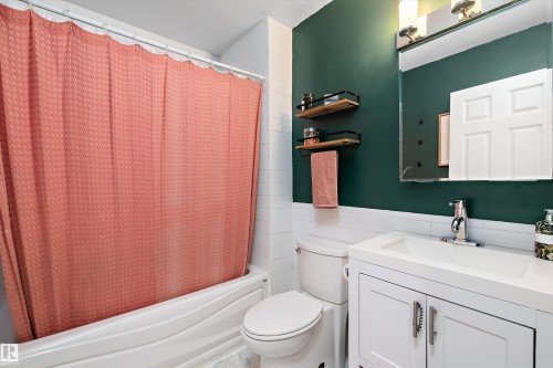 Full bathroom with tile walls, vanity, shower / bath combo with shower curtain, and wainscoting - 12 Beacon Crescent, St. Albert, AB - Indoor Photo Showing Bathroom
