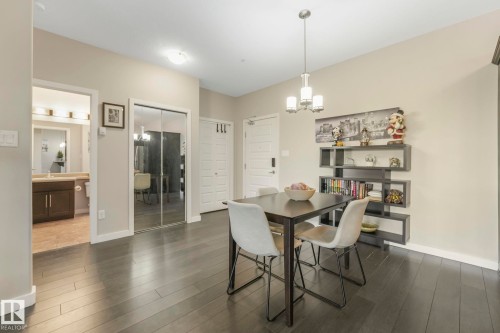 Dining space with dark wood-style flooring and suspended lighting - 122 304 Ambleside Link Link, Edmonton, AB - Indoor Photo Showing Dining Room