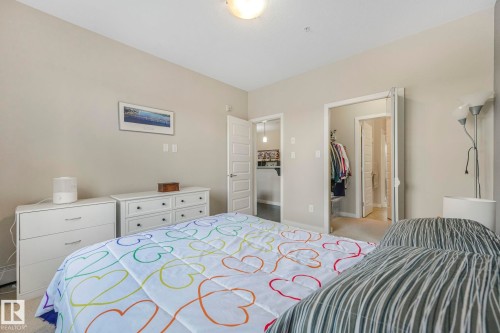 Bedroom featuring light colored carpet and a walk in closet - 122 304 Ambleside Link Link, Edmonton, AB - Indoor Photo Showing Bedroom