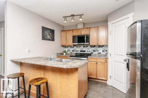 Kitchen with stainless steel appliances, light countertops, tasteful backsplash, a breakfast bar, and rail lighting - 1381 Rutherford Road, Edmonton, AB - Indoor Photo Showing Kitchen